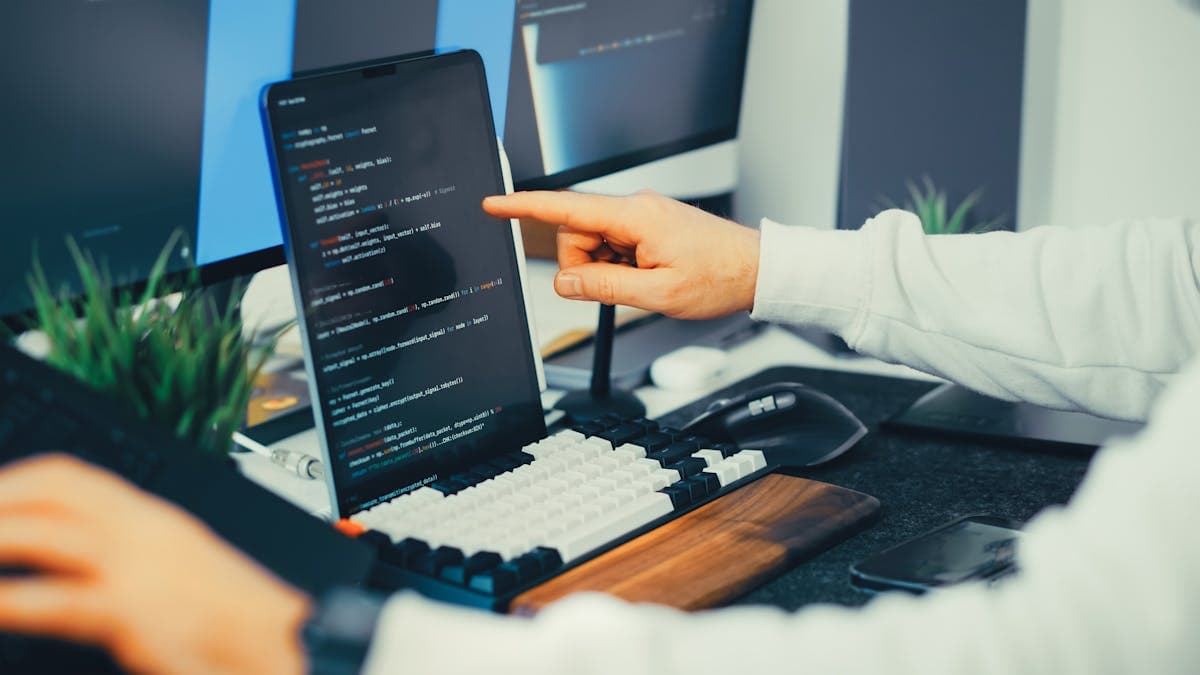 Developer working on workflow automation with laptop and monitor setup